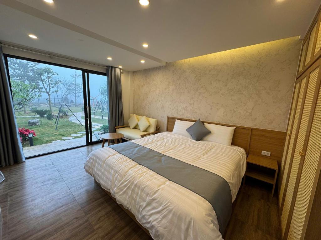a bedroom with a large bed and a large window at The C'mon Mộc Châu in Làng Môn
