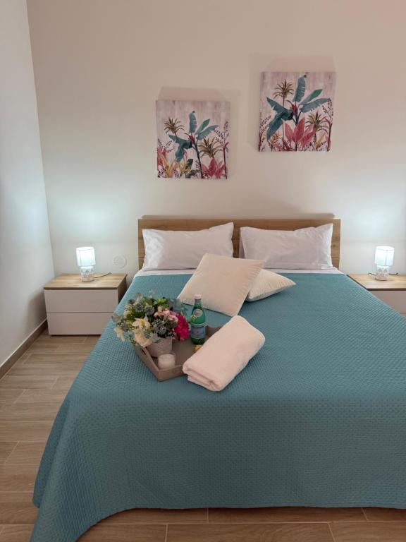 a bed with a blue blanket and flowers on it at Casa Vacanze Nicol in Licata