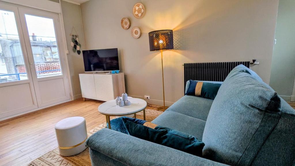 a living room with a blue couch and a table at Le Saint-Georges in Berck-sur-Mer