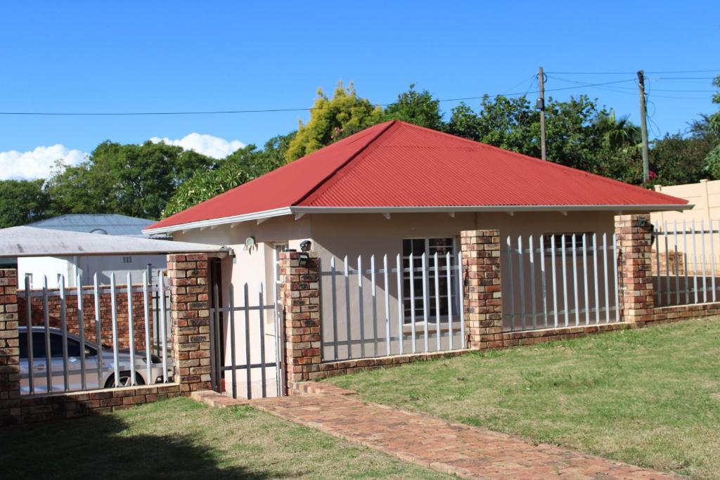 a house with a fence and a red roof at Thami residence - Self catering in Grahamstown