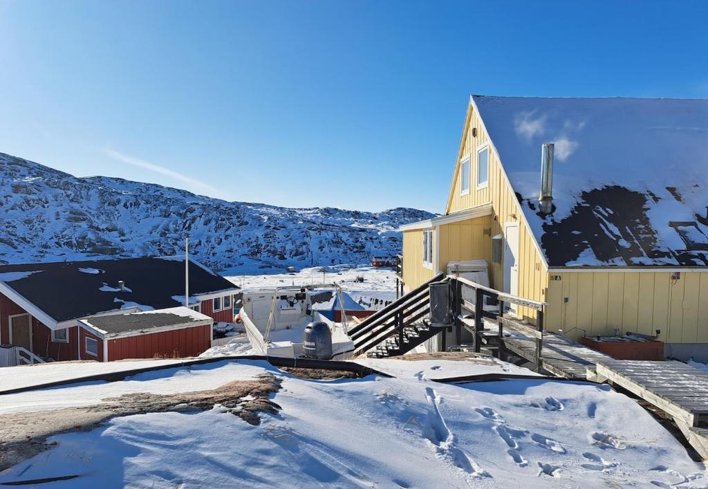 a church covered in snow next to a mountain at Michelle's Yellow house in Ilulissat