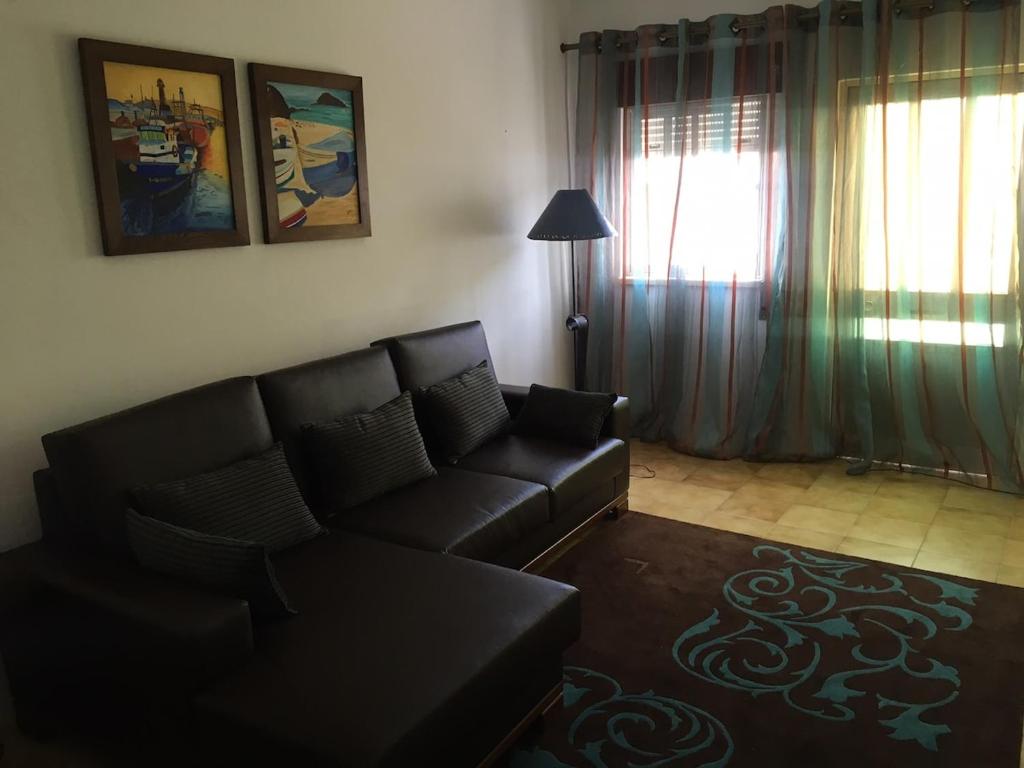 a living room with a black couch and a window at Lovely grandma house in Vila Viçosa
