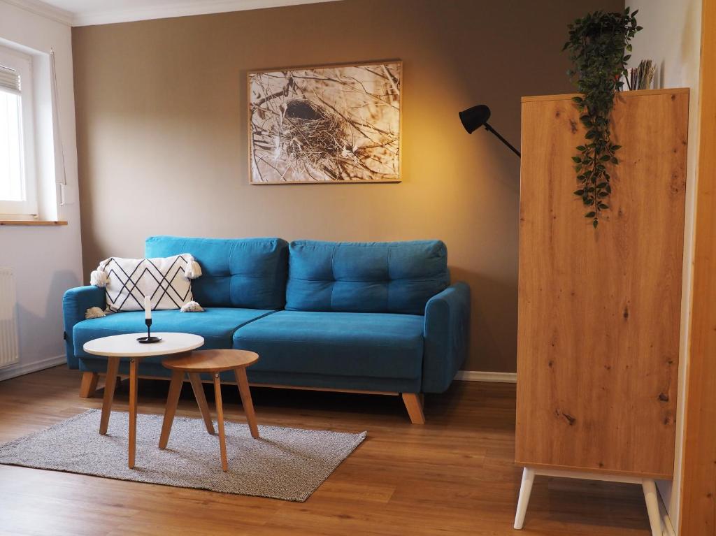 a living room with a blue couch and a table at Ferienwohnung Siedlungsnest in Anklam