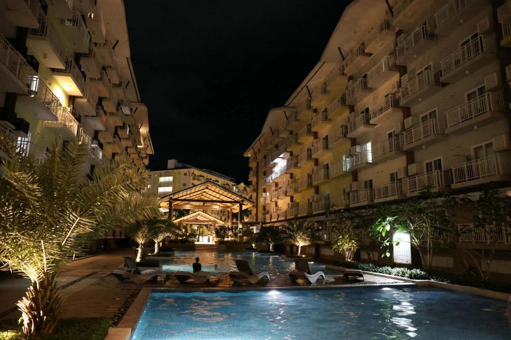 a swimming pool in the middle of two buildings at night at Iam Cozy Condo Mactan Airport in Lapu Lapu City