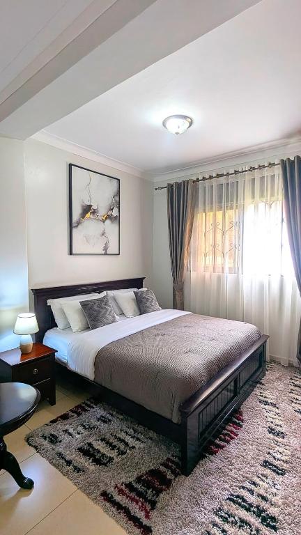 a bedroom with a large bed and a window at Vine Vale in Kampala