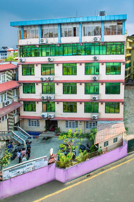 a tall building with green windows and a balcony at Rameshworam Hotel in Kathmandu