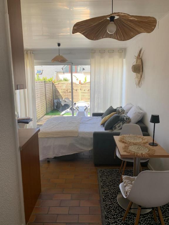 a bedroom with a bed and a couch and a table at Waterfront studio with small garden, pool, parking in Guidel