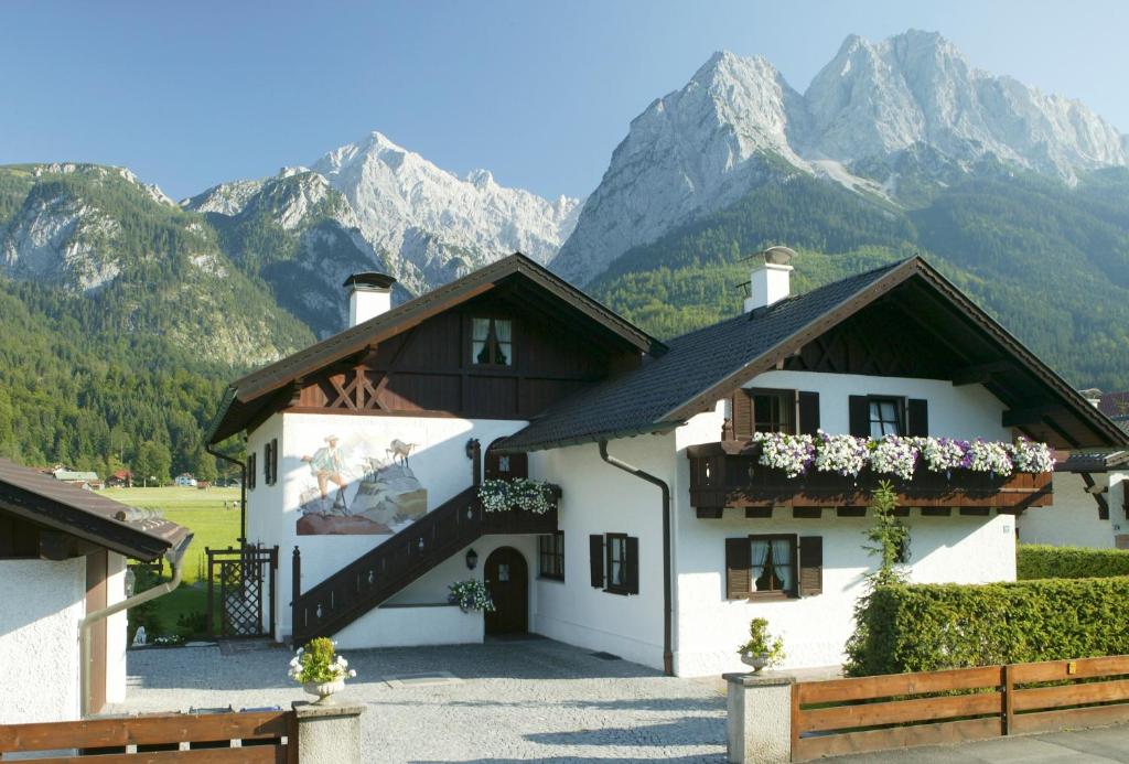 a white house with mountains in the background at Frühholz - Das Ferienhaus - in Grainau