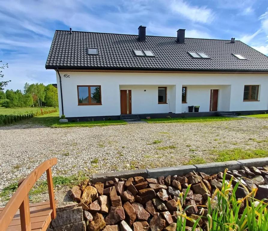 a white house with a fence and a stone wall at Apartamenty Ku Dolinie in Wilków