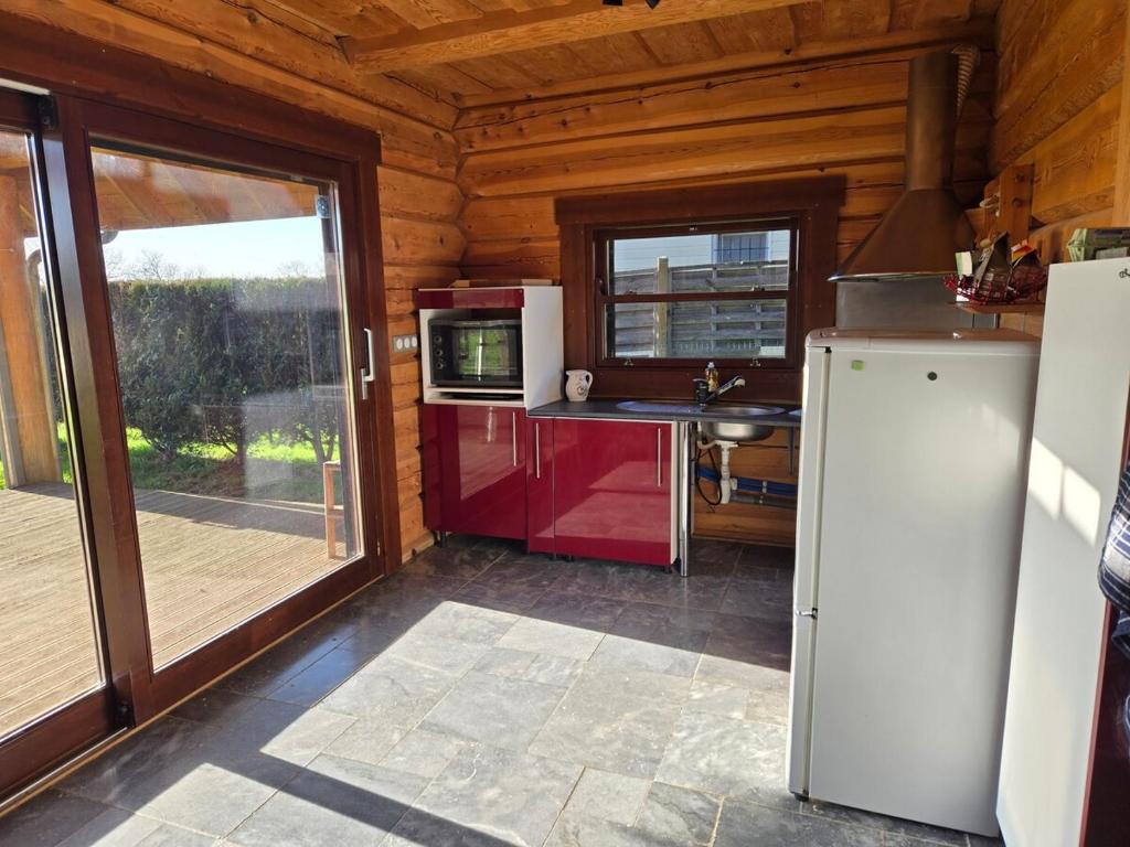 a kitchen with a refrigerator and a window in a cabin at Charmante Fuste in Lubersac