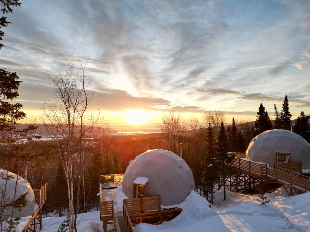 two domes in the snow with the sunset in the background at Nørdika Charlevoix in Baie-Saint-Paul