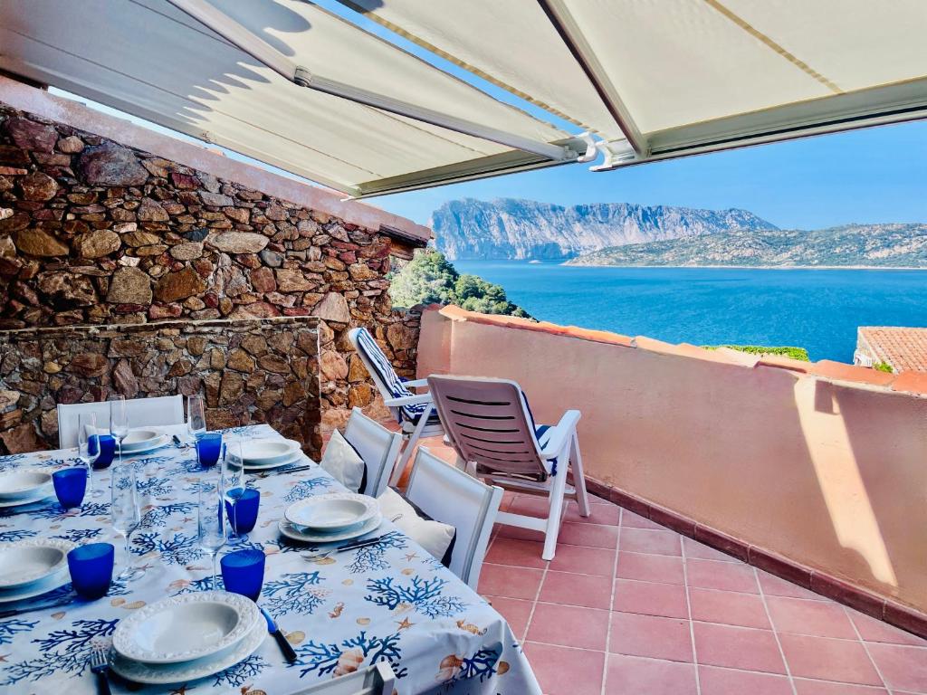 a table and chairs on a balcony with a view of the ocean at Punta Est - Trilo LAVANDA Terrazza & Piscina in Capo Coda Cavallo