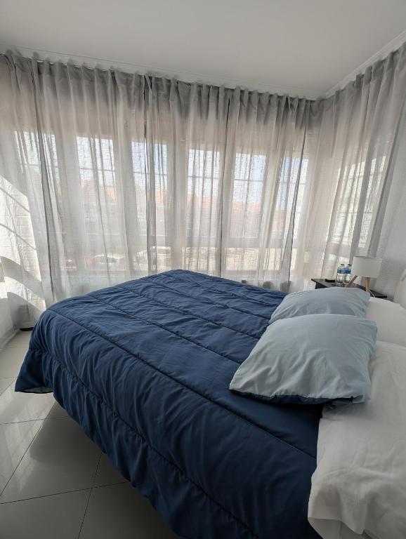 a bedroom with a bed with blue sheets and windows at Alojamiento La Ballena in Santoña
