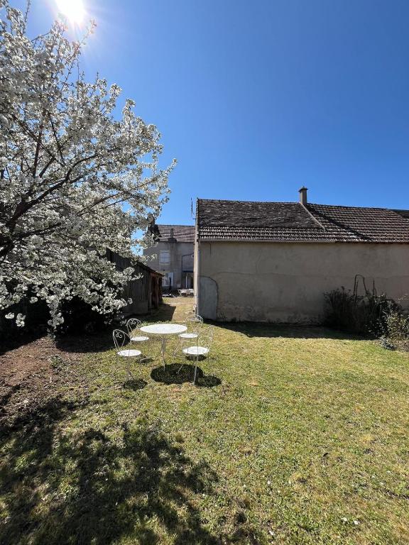 two chairs and a table in a yard with a tree at Gîte Chez Mamie Madeleine in Ainay-le-Château