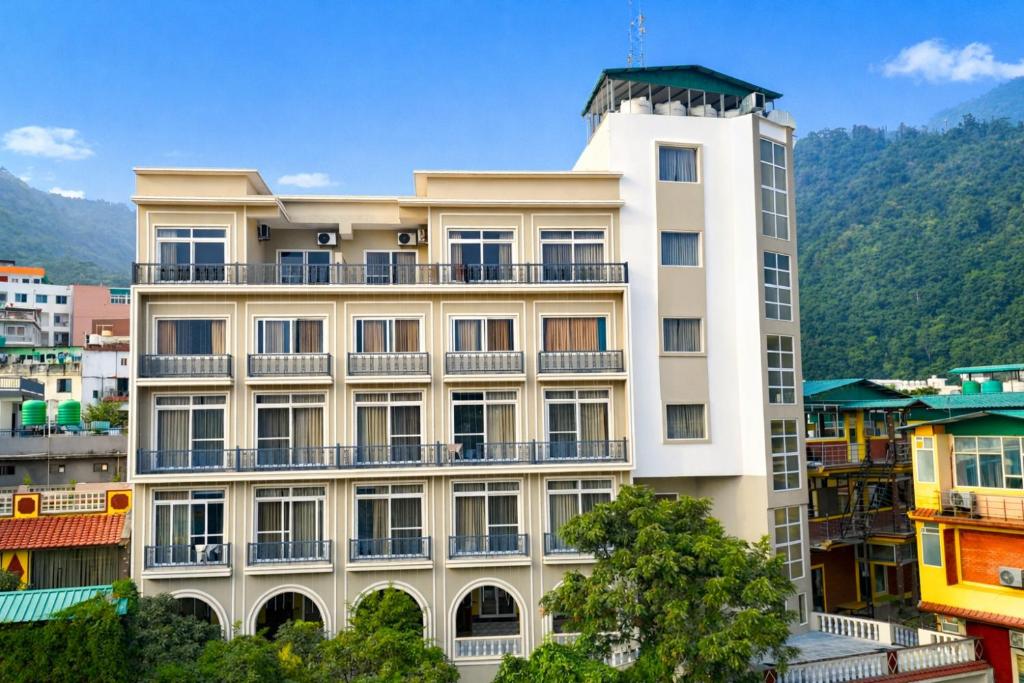 a white building with balconies on the side of it at MVT Guesthouse & Restaurant (Rishikesh) in Rishīkesh