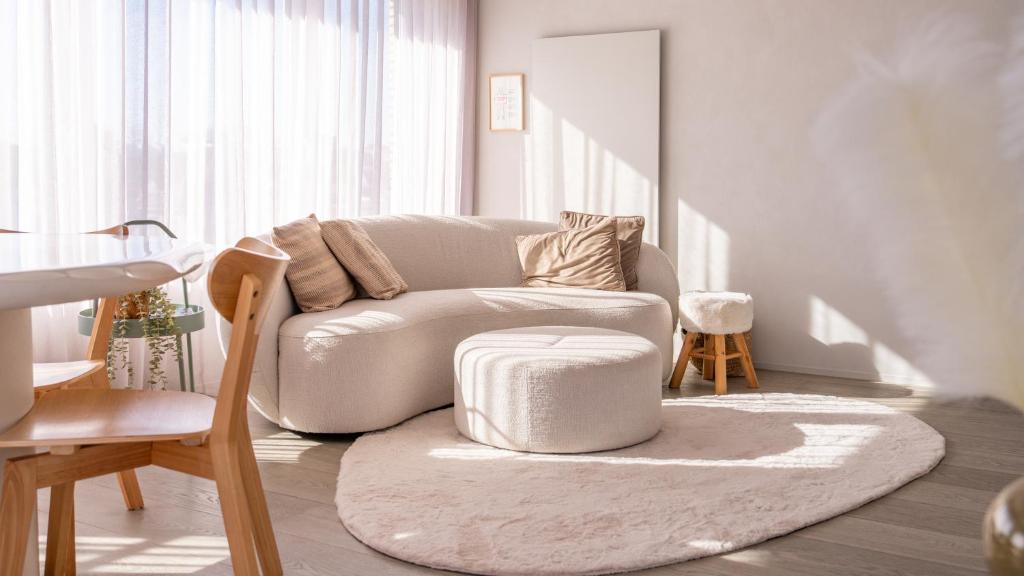 a white living room with a couch and a stool at Groenendijk 8 in Oostduinkerke