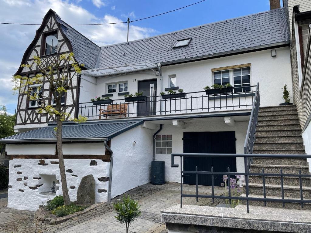 a white house with a balcony and stairs at Ferienhaus Mediterran in Bruttig-Fankel für 2-5 Personen in Bruttig-Fankel