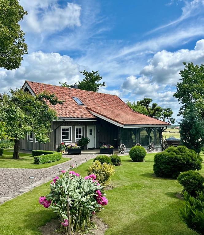 a house with a green yard with flowers at Sodyba Viltis in Bikavėnai