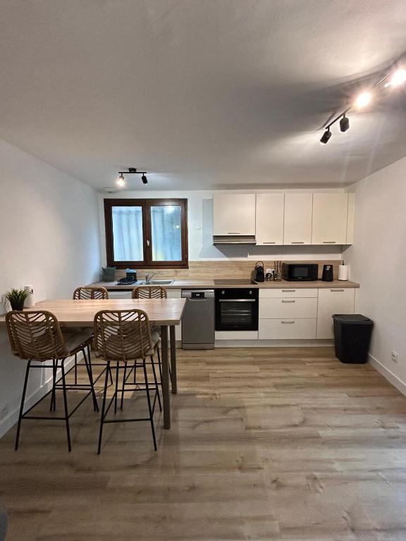 a kitchen with white cabinets and a wooden table and chairs at Panach in Saint-Loubès