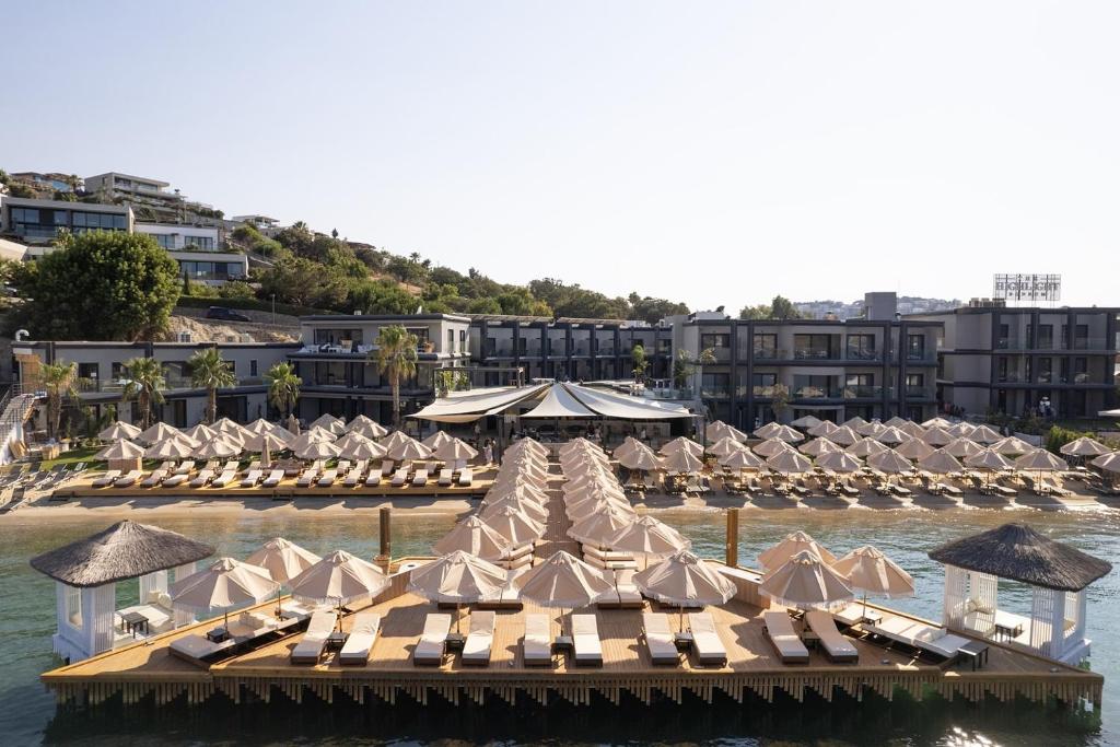 a bunch of lounge chairs and umbrellas in the water at The Sign Highlight Hotel in Bodrum City