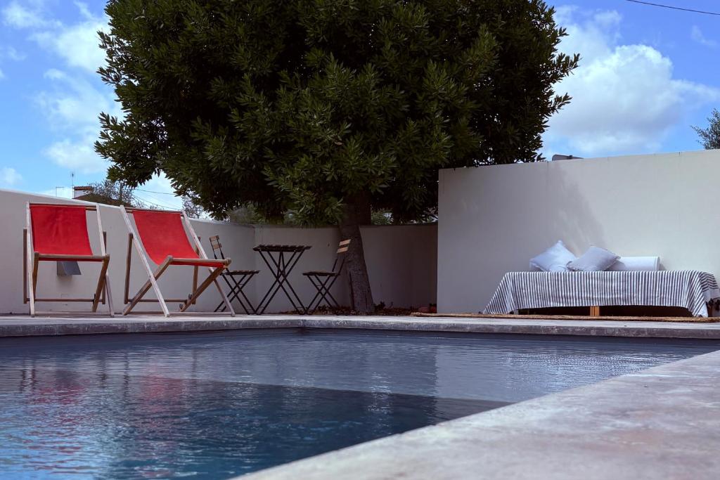 a swimming pool with chairs and a table and a fence at Casa da Mata in Torres Novas
