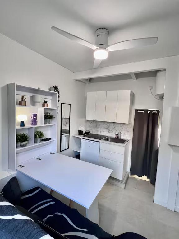 a kitchen with white cabinets and a white table at Mini-studio de 15m2 à 8 min de Paris in Maisons-Alfort