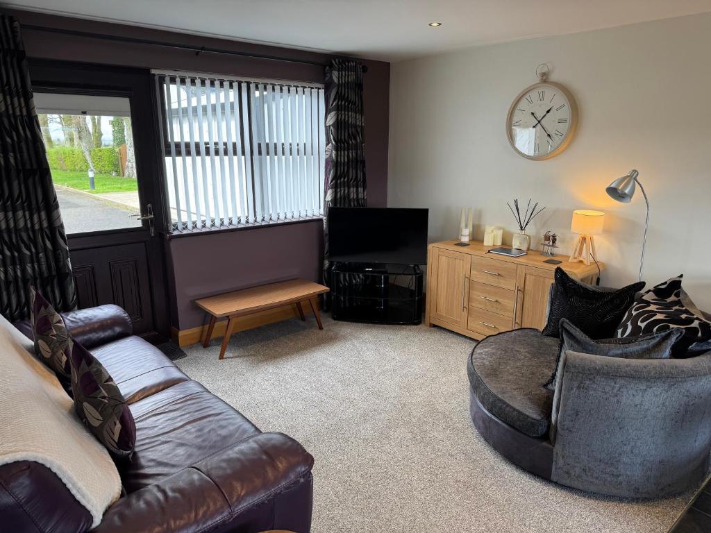 a living room with a couch and a clock on the wall at Marions Place in Finvoy