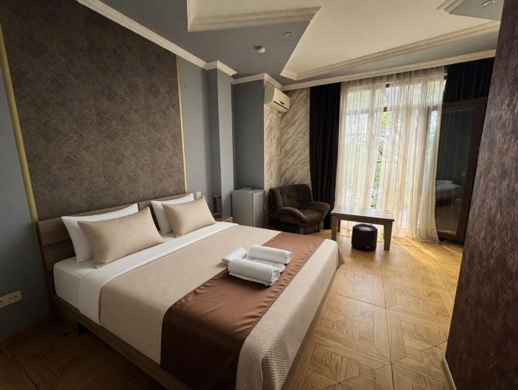 a bedroom with a large bed and a chair at Hotel Elite in Batumi