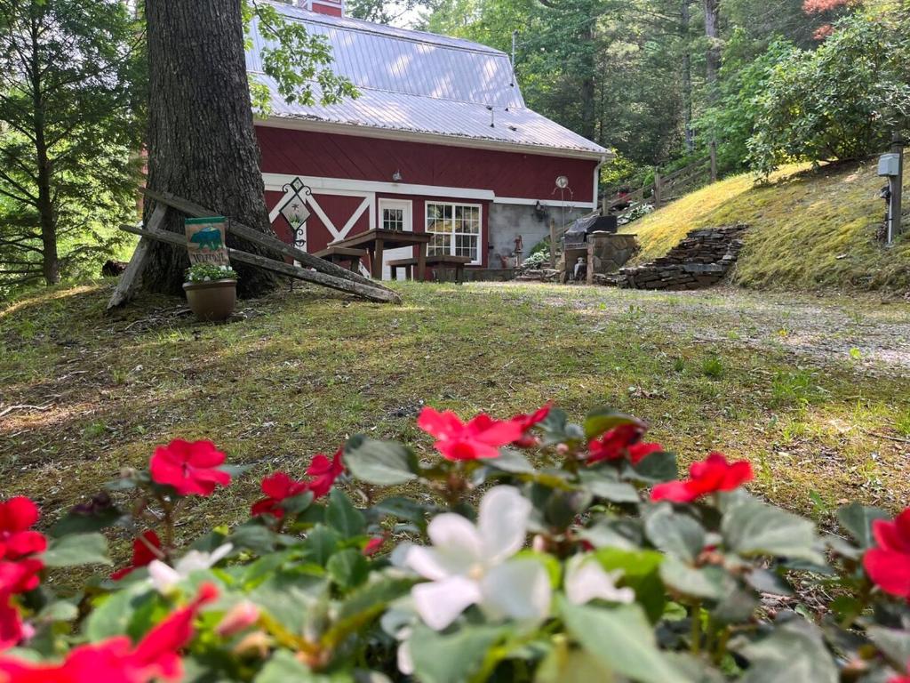 a house with red and white flowers in front of it at Charming Rustic Barn in Spruce Pine