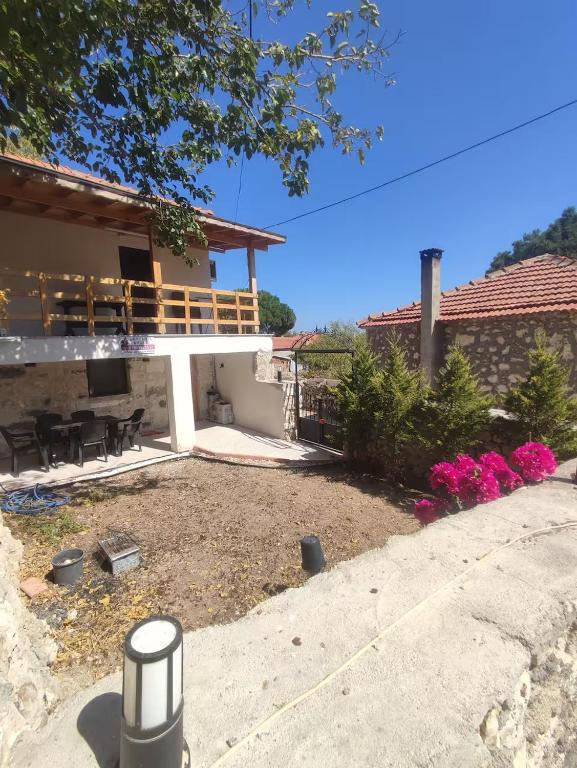 a house with a porch and a patio with pink flowers at Begonvil Evleri Karaburun in Karaburun
