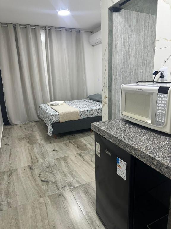 a small room with a microwave and a bed at Henri Karam in Brumadinho