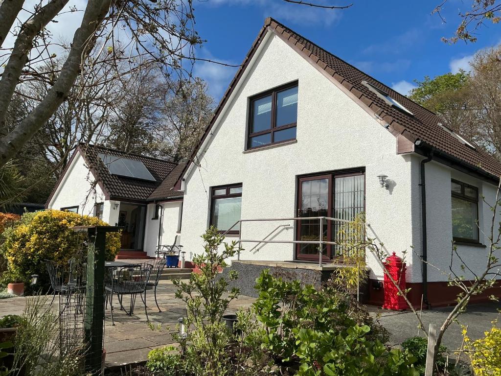ein weißes Haus mit schwarzen Fenstern und einer Terrasse in der Unterkunft Ardenlea in Kyle of Lochalsh