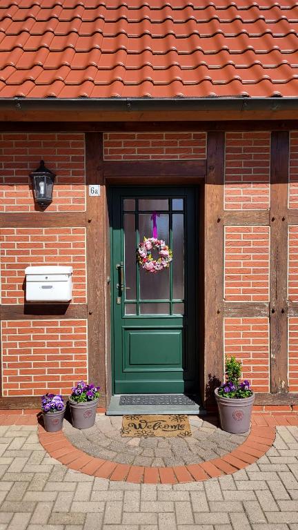 a green door on a brick building with flowers at Ferienwohnung am Hünenweg in Berge