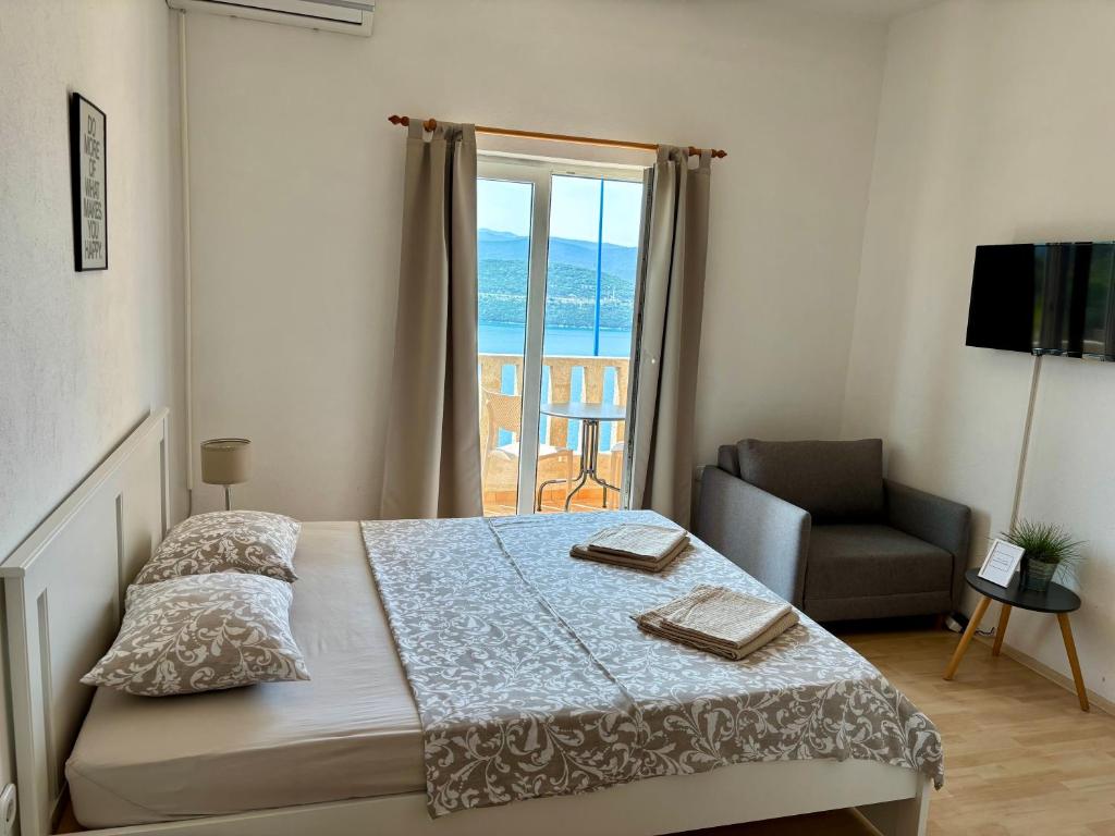 a bedroom with a bed and a chair and a window at Apartments Ela in Neum