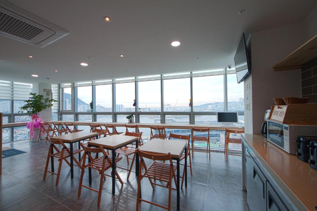 a kitchen with a long bar with stools and tables at K-Guesthouse Premium Nampo 1 in Busan