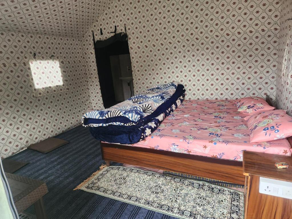 a small bedroom with a bed with pink sheets at New Kufari Apple Valley camping in Shimla