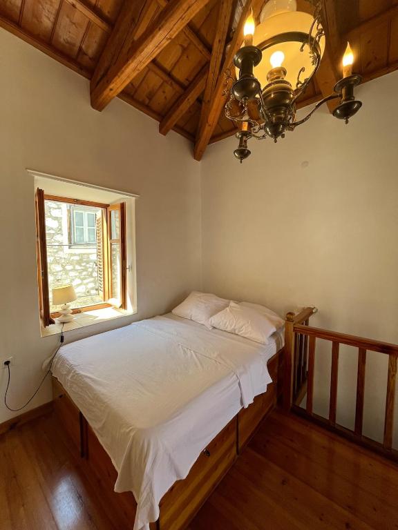 a bed in a room with a window and a chandelier at HYDRA Central House in Hydra