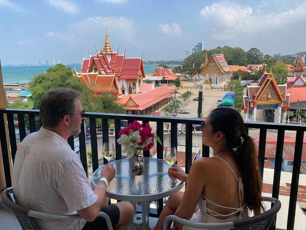 a man and a woman sitting at a table on a balcony at Beach Front Condo Centerviews Bangsaray Floor 6 in Bang Sare
