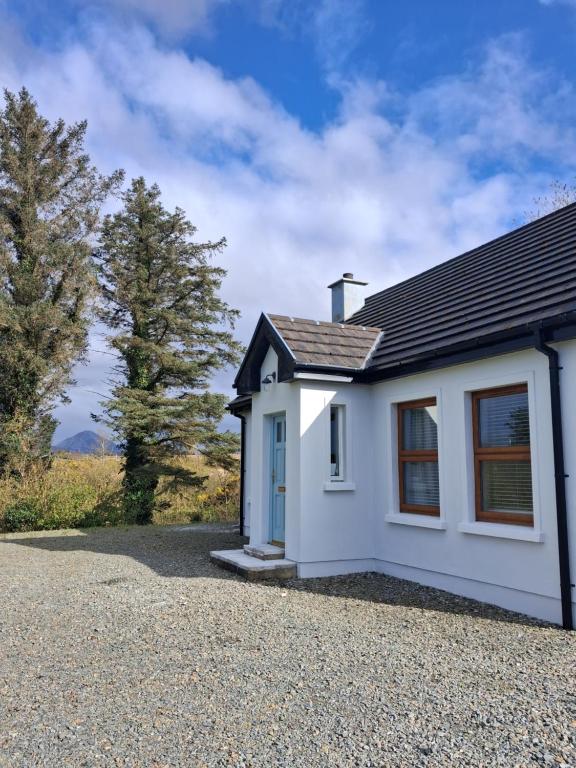 a small white house with a gravel driveway at River Cottage Donegal in Bunbeg