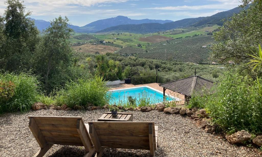 a swimming pool in a yard with two chairs and a table at Casa del Sueño - Casitas met uitzicht in Alora