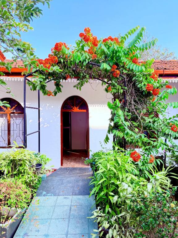 an archway with red flowers on a building at Garden Cottage Homestay BB in Wattala