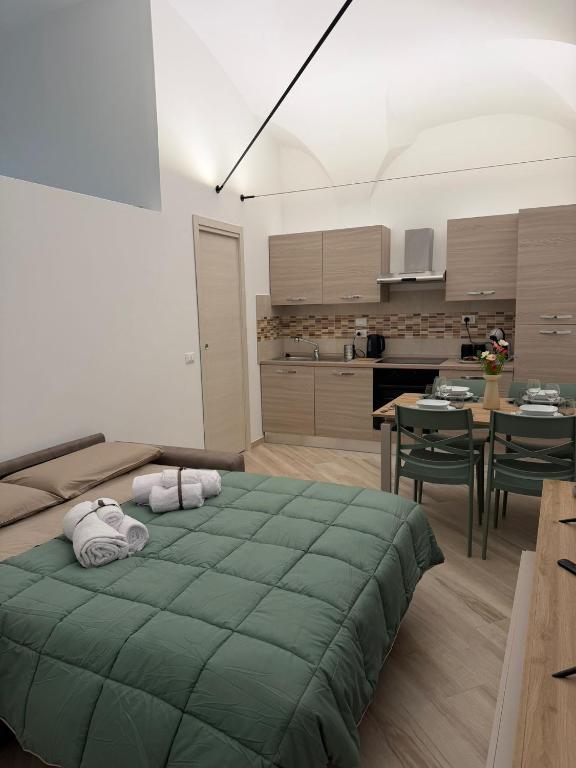 a bedroom with a green bed and a kitchen at Dimora Piazza Palazzo in LʼAquila