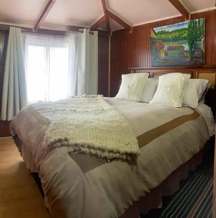 a large bed in a bedroom with a window at Hostal Art Gallery Chiloè in Castro
