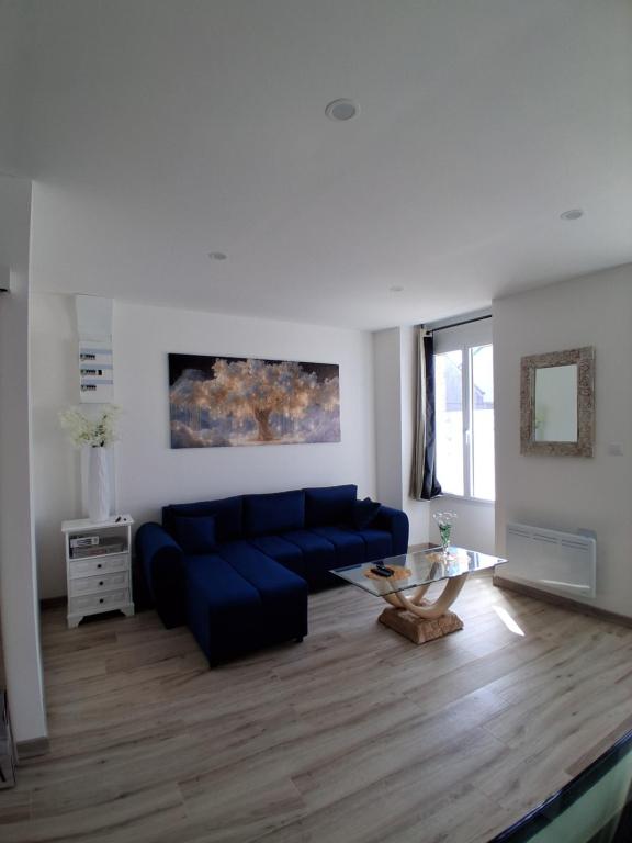 a living room with a blue couch and a glass table at rozormant in Rosporden