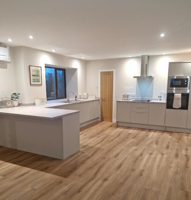 a large kitchen with white counters and a wooden floor at Quholmslie Farm Self-Catering in Stromness