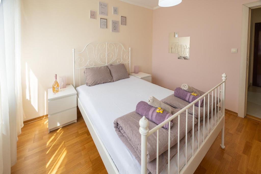 a white bed with purple pillows in a bedroom at Apartment Orchid 021 in Novi Sad