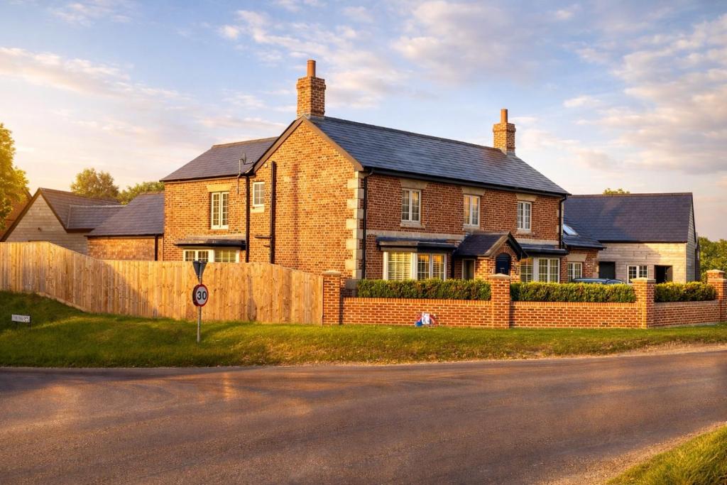 a brick house with a fence in front of it at The Old Pub Wiltshire A Unique Luxury Cellar Retreat with Private Sauna Gym and Movie Room in Patney