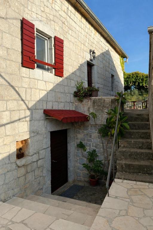 a building with red shutters and a door and stairs at Villa Sunrise in Herceg-Novi