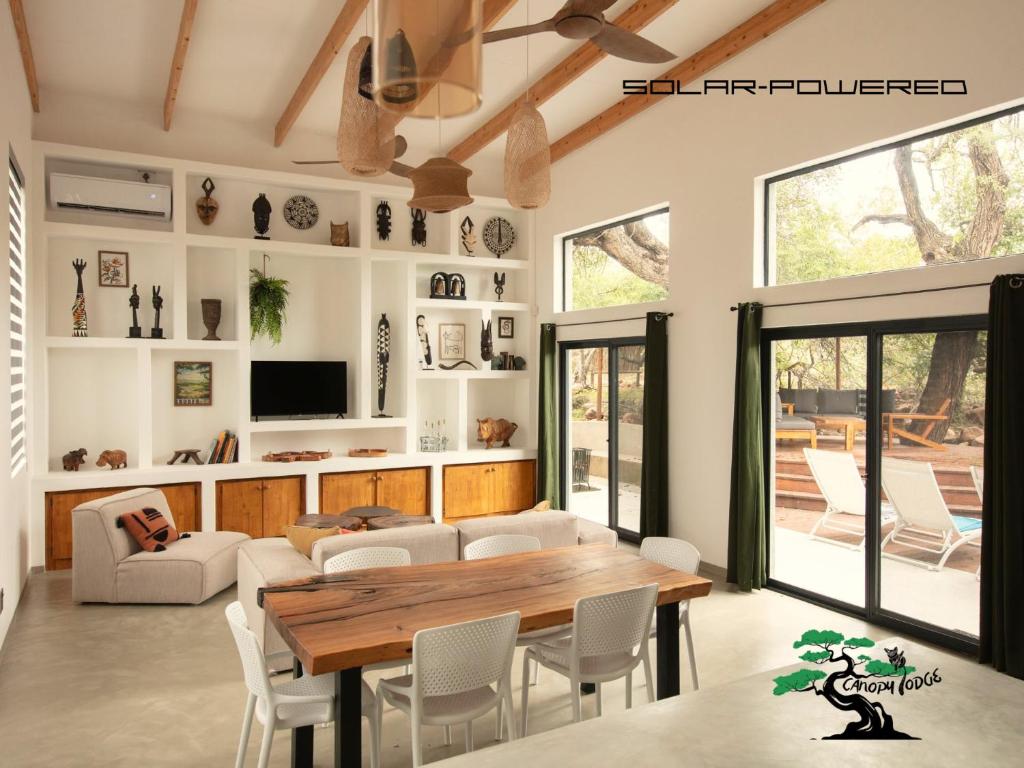 a living room with a wooden table and chairs at Canopy Lodge Marloth in Marloth Park