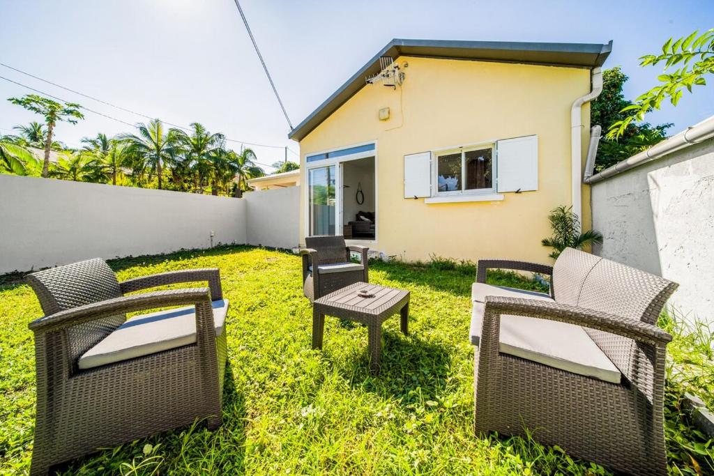 a backyard with wicker chairs and a table at Villa Cocon Jacuzzi in Saint-Pierre